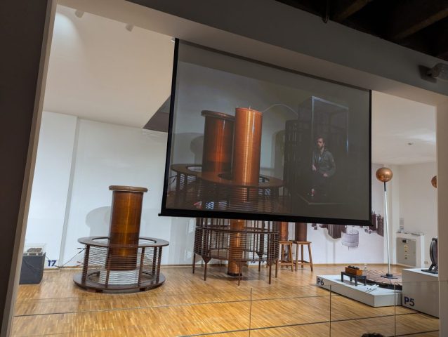 bobinele-lui-tesla-in-actiune-demonstratii-spectaculoase-la-muzeul-tehnic Demonstrație cu bobine Tesla într-o sală a muzeului tehnic din Zagreb, cu o cușcă Faraday pe ecran