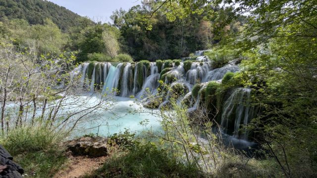 cascada-skradinski-buk-vedere-naturala-parc-national-krka Cascada Skradinski Buk din Parcul Național Krka, Croația, văzută prin vegetație verde.