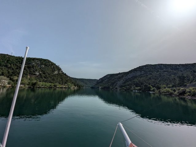 croaziera-pe-raul-krka-skradin-croatia Peisaj de croazieră pe râul Krka, cu dealuri împădurite și ape calme în apropiere de Skradin, Croația.