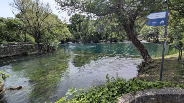 plimbare-parcul-national-krka-croatia-natura-traseu-apa Traseu de plimbare în Parcul Național Krka, Croația, cu vedere spre apa cristalină și semnalizare turistică.